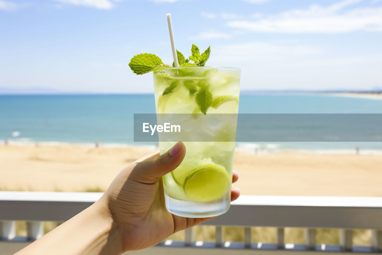 soft drink, refreshment, drink, sea, food and drink, beach, hand, cocktail, water, mojito, sky, drinking glass, alcohol, land, glass, household equipment, fruit, leaf, nature, holding, horizon over water, horizon, alcoholic beverage, mint leaf - culinary, lemon, drinking straw, food, vacation, straw, trip, tropical climate, summer, one person, citrus fruit, focus on foreground, freshness, herb, day, holiday, adult, outdoors, sunlight, tropical drink, close-up, rum, cloud, sand, lime, caipiroska, healthy eating, travel destinations, travel, beauty in nature, plant part, leisure activity, lifestyles, cold temperature, juice, distilled beverage, hard liquor, tourist resort, produce