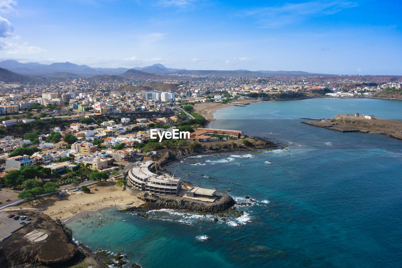 HIGH ANGLE VIEW OF SEA BY BUILDINGS AGAINST SKY