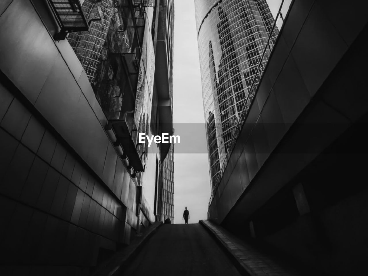 Low angle view of people walking on footpath amidst buildings