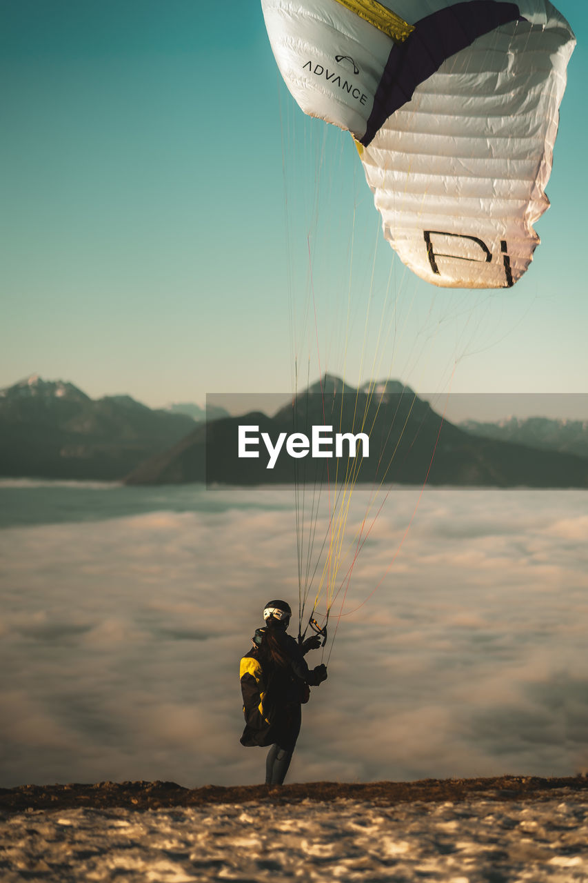 MAN PARAGLIDING AGAINST SKY