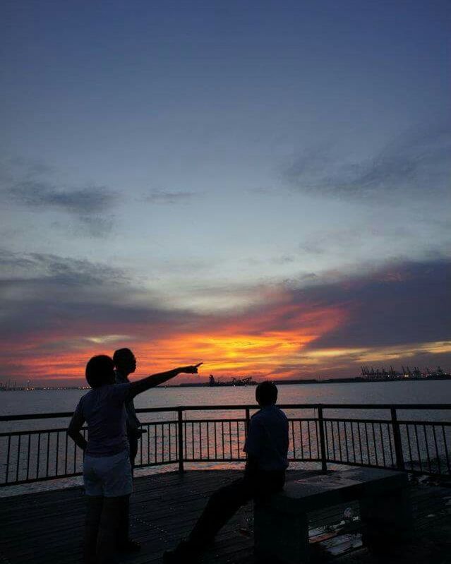 SILHOUETTE OF PEOPLE STANDING ON RAILING