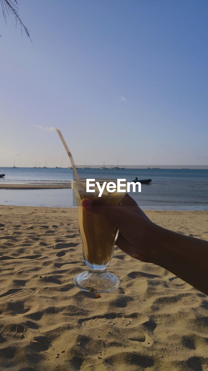 MAN DRINKING GLASS ON BEACH