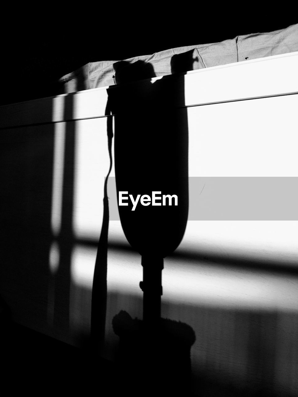 LOW ANGLE VIEW OF LIGHT BULB HANGING ON SILHOUETTE METAL