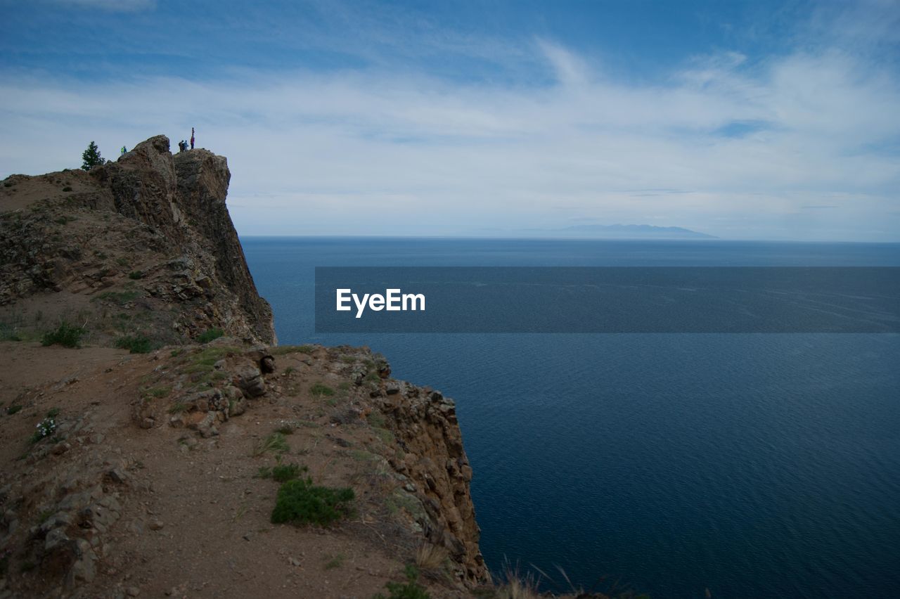 Scenic view of sea by cliff against sky