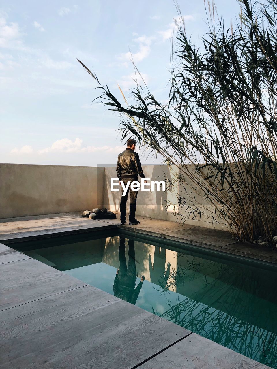 Man standing by swimming pool against sky