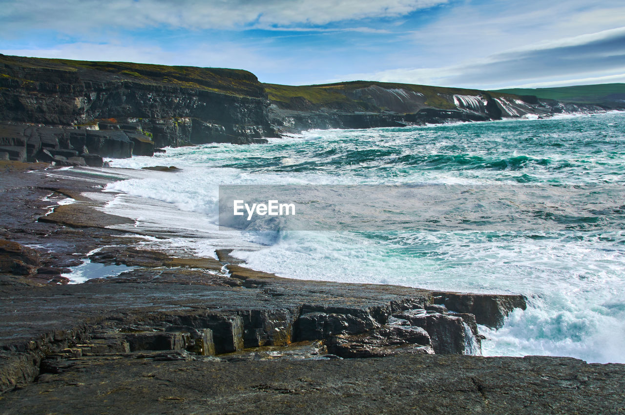 SCENIC VIEW OF ROCKY BEACH AGAINST SKY