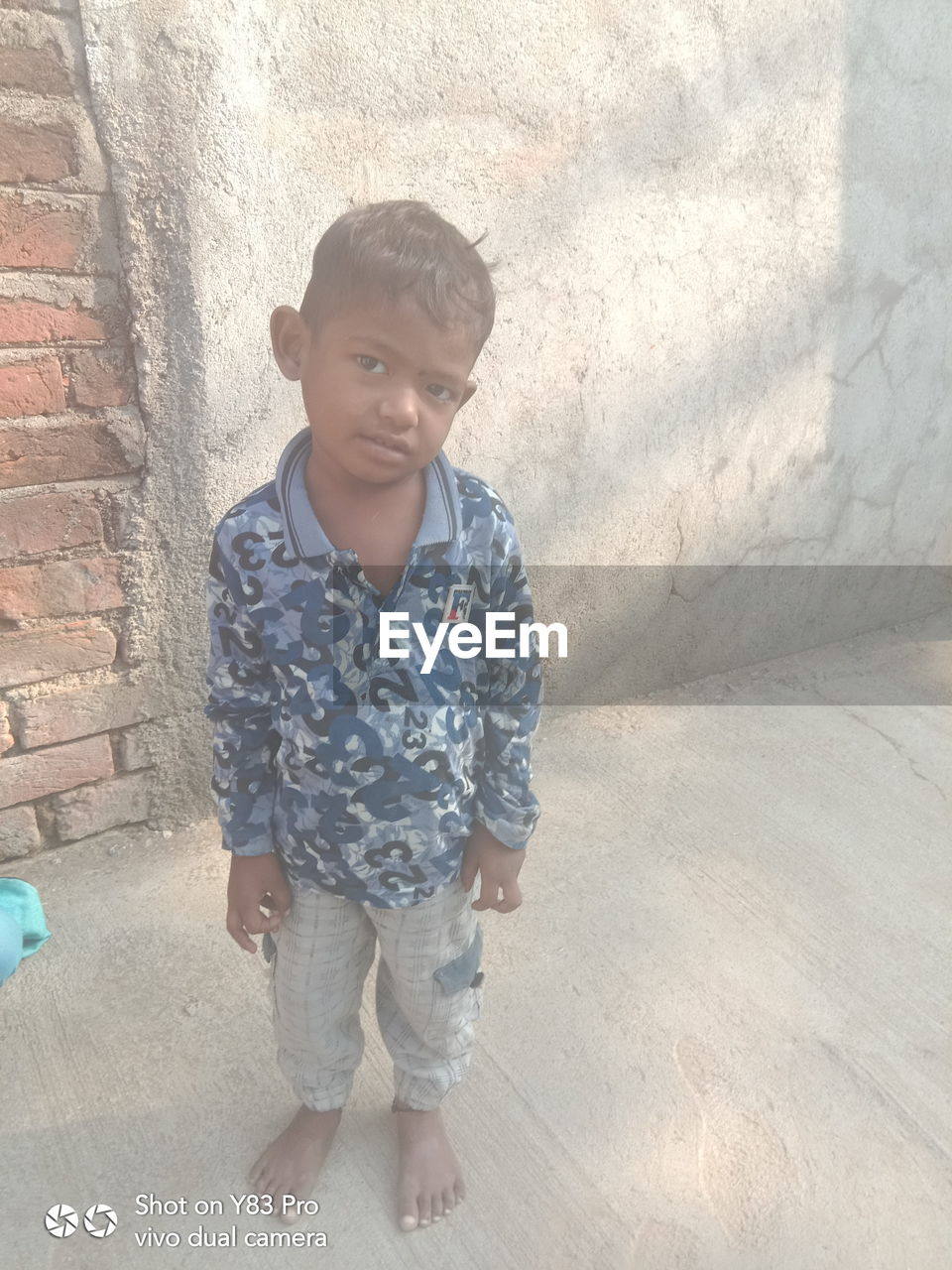 PORTRAIT OF A BOY STANDING AGAINST WALL