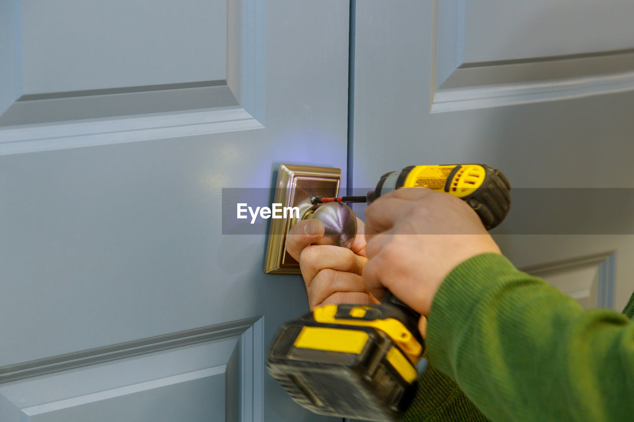 Cropped hand of person repairing doorknob