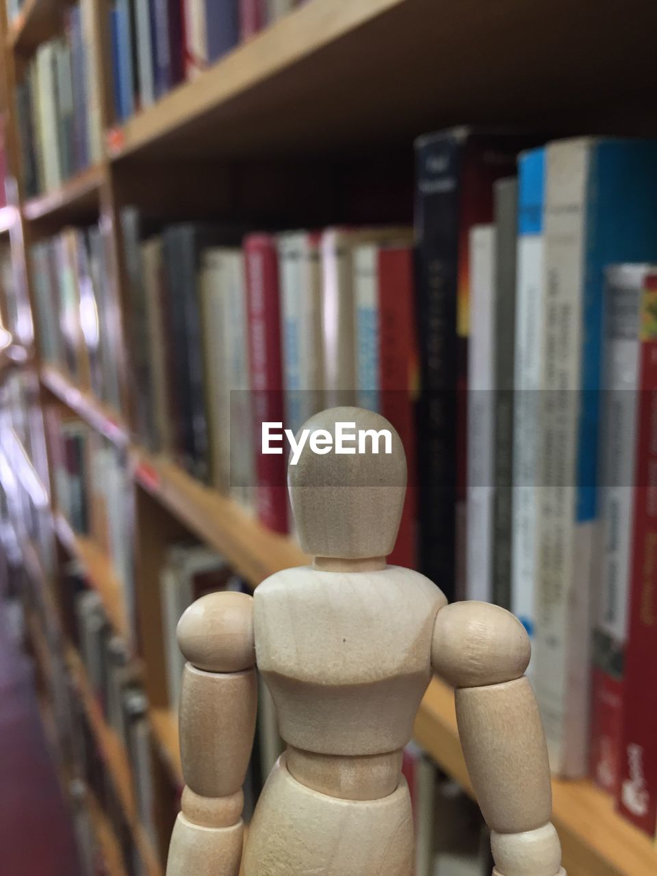 Close-up of figurine against bookshelf at library
