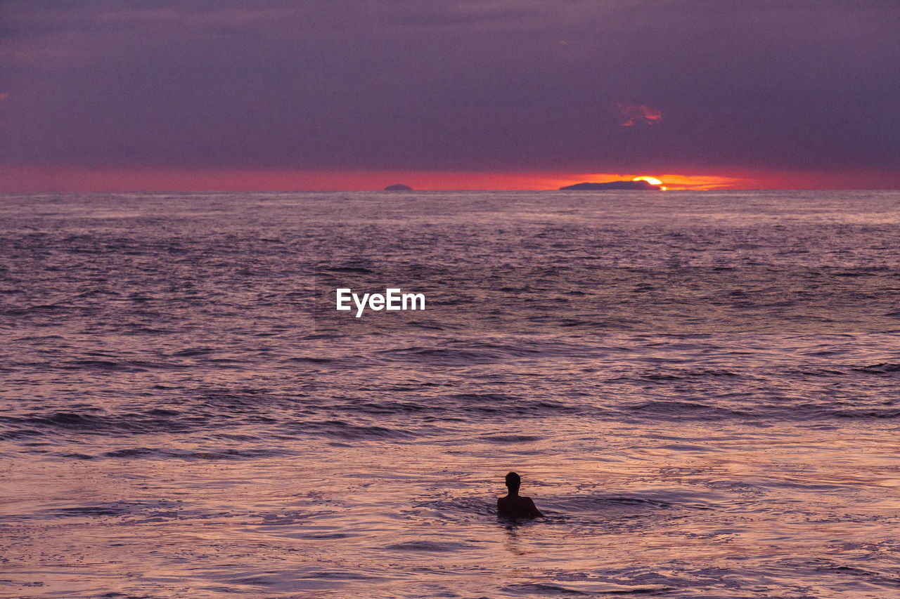 Silhouette man swimming in sea during sunset