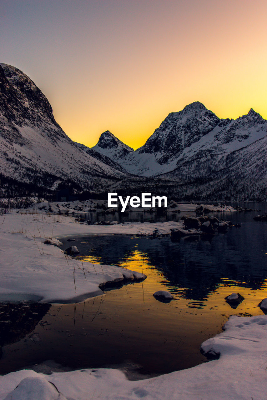 Scenic view of frozen lake against mountains during sunset