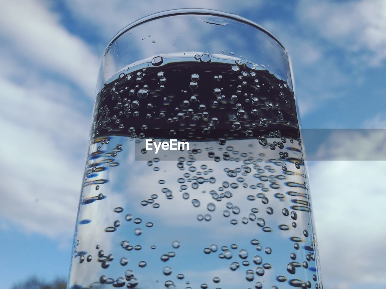 CLOSE-UP OF GLASS OF WATER AGAINST SKY