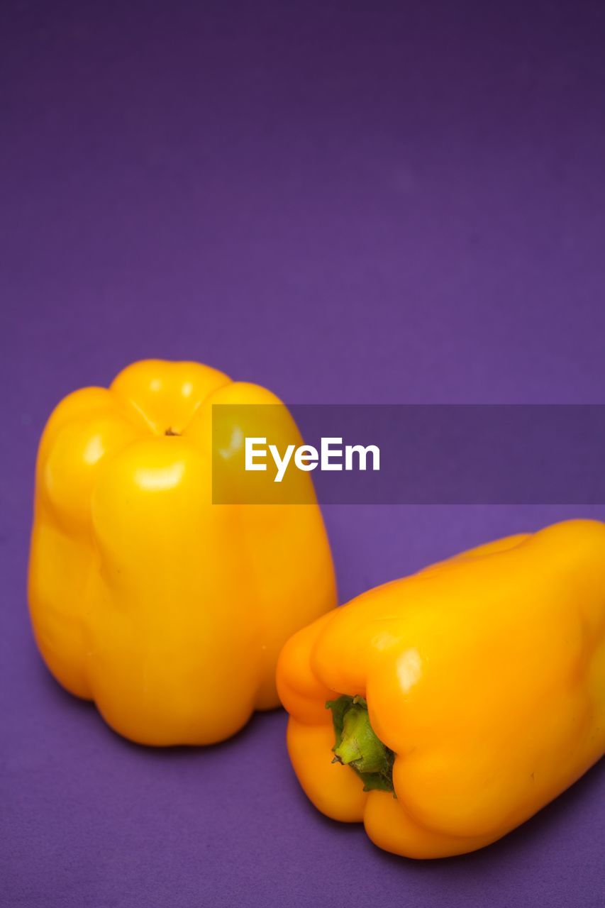 Two yellow bell peppers on purple background