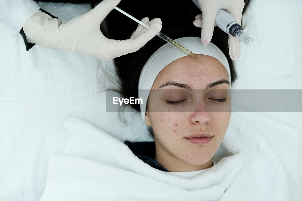 Cosmetologist applying face serum, preparing skin for microneedling