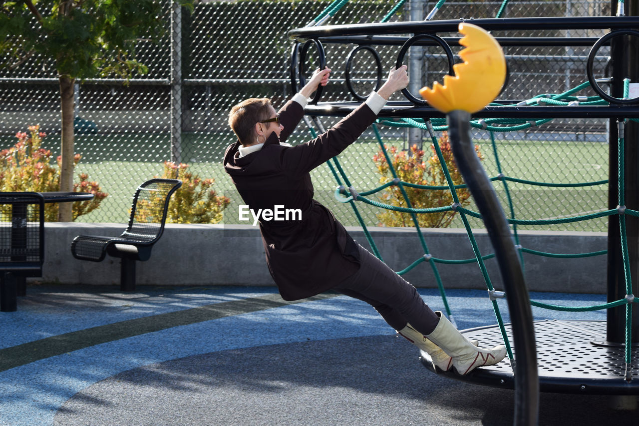 Full length of playful woman on merry-go-round at park