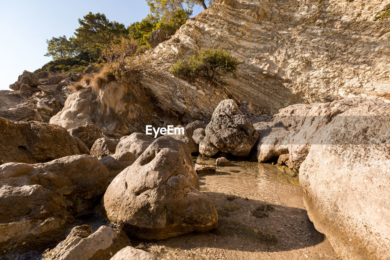 Large white stones in azure water against the background of rocks