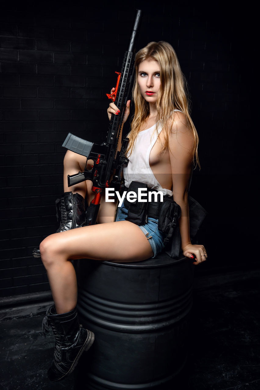 Portrait of a beautiful young woman sitting against black background