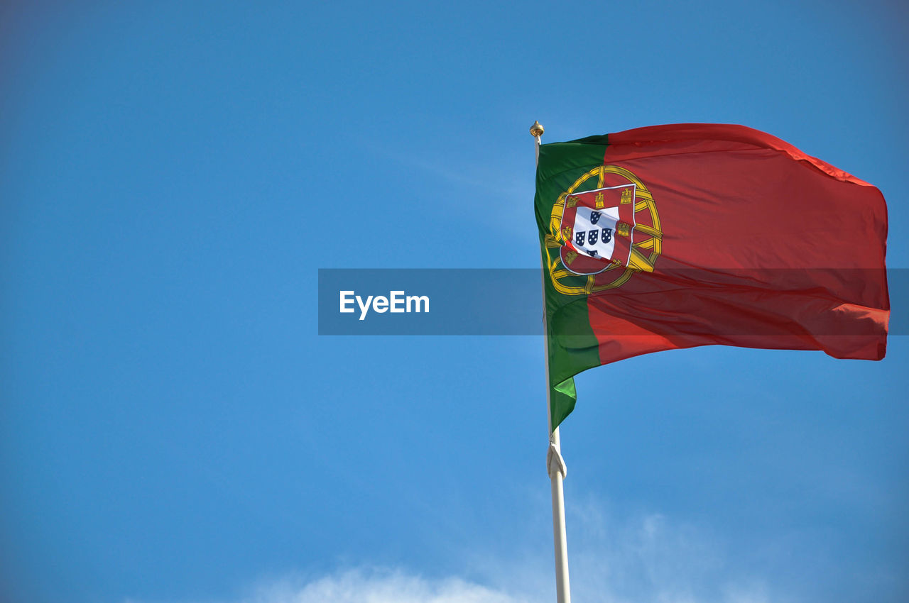 Low angle view of flag against blue sky