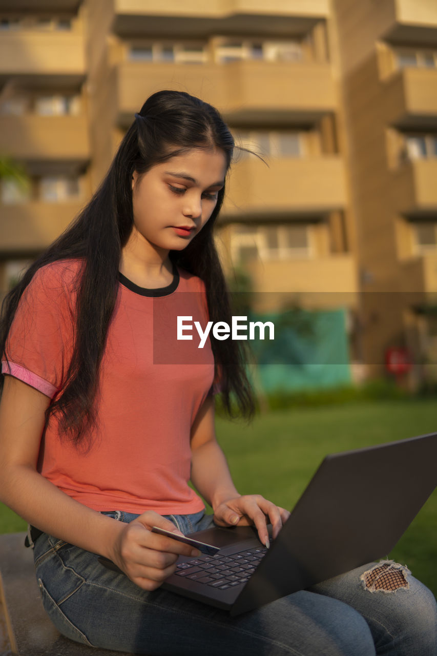 young woman using laptop while sitting on sofa