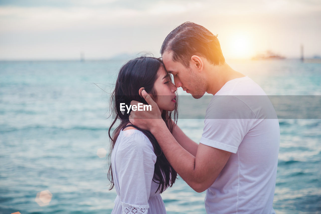 YOUNG COUPLE KISSING AGAINST SEA