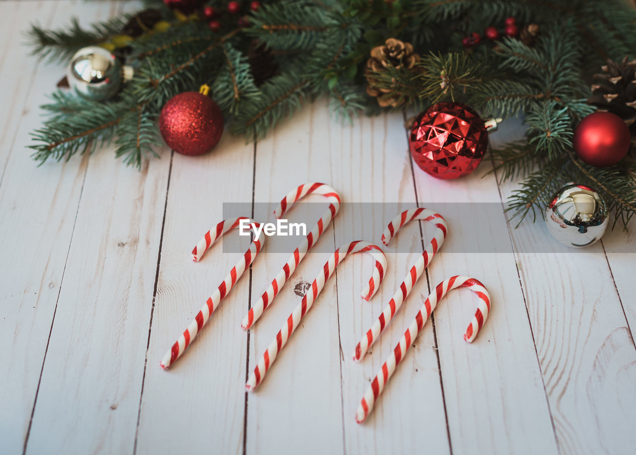 Candy canes on white wood backdrop with christmas decorations.