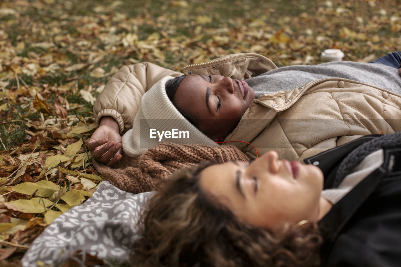 Female friends relaxing on blanket at autumn