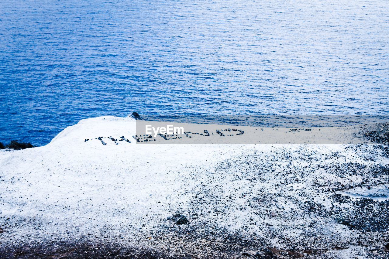 High angle view of text on rock against sea