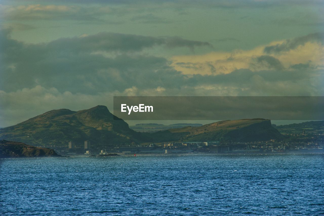SCENIC VIEW OF SEA AGAINST MOUNTAIN