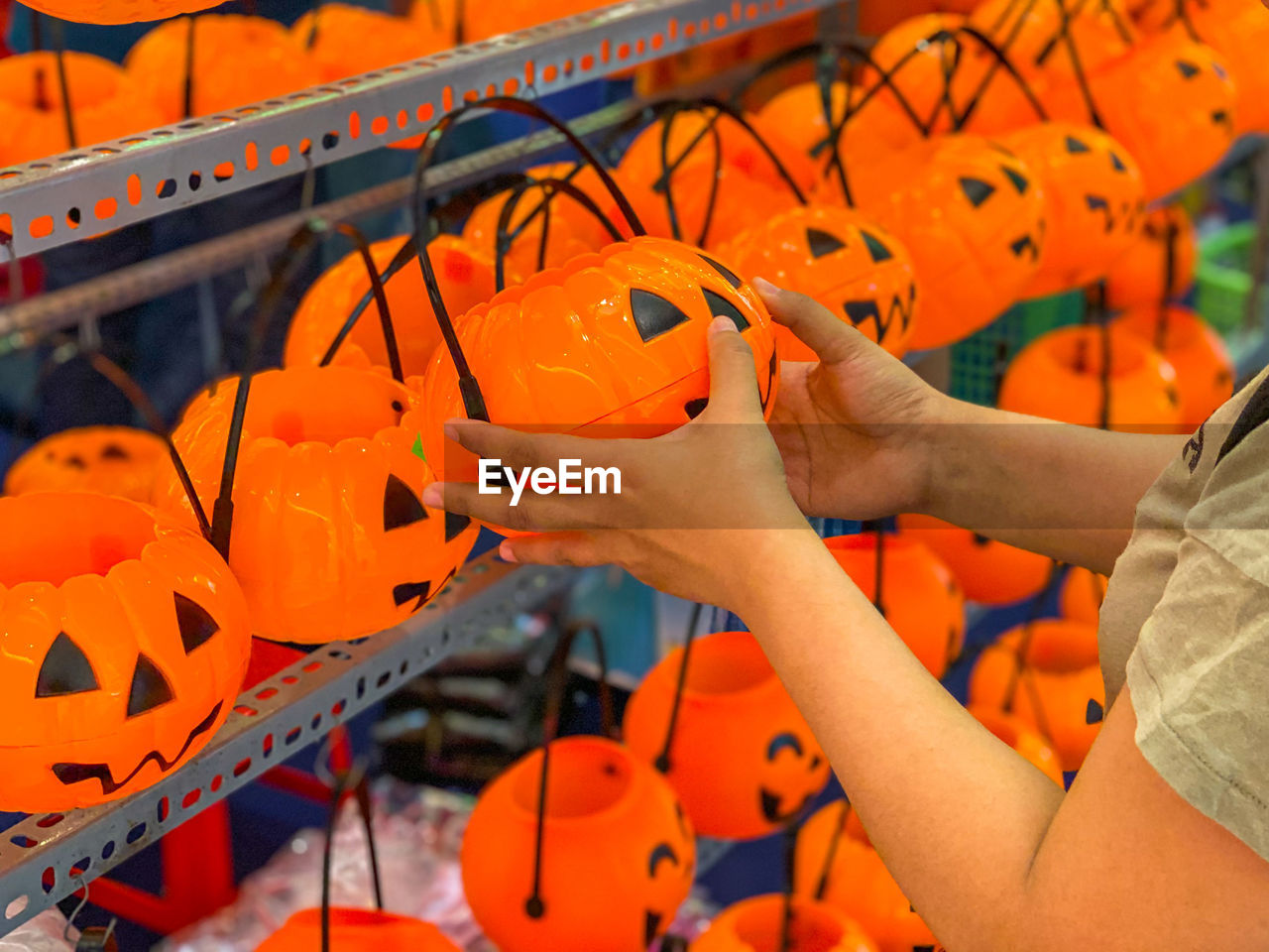 Woman choosing pumpkin jack o lantern at halloween accessories shop