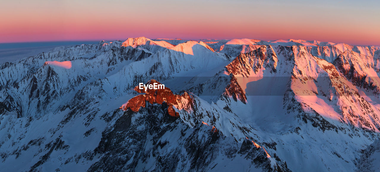 Scenic view of snow covered mountains during sunset