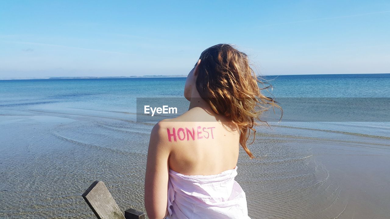 Rear view of woman with text on back at beach