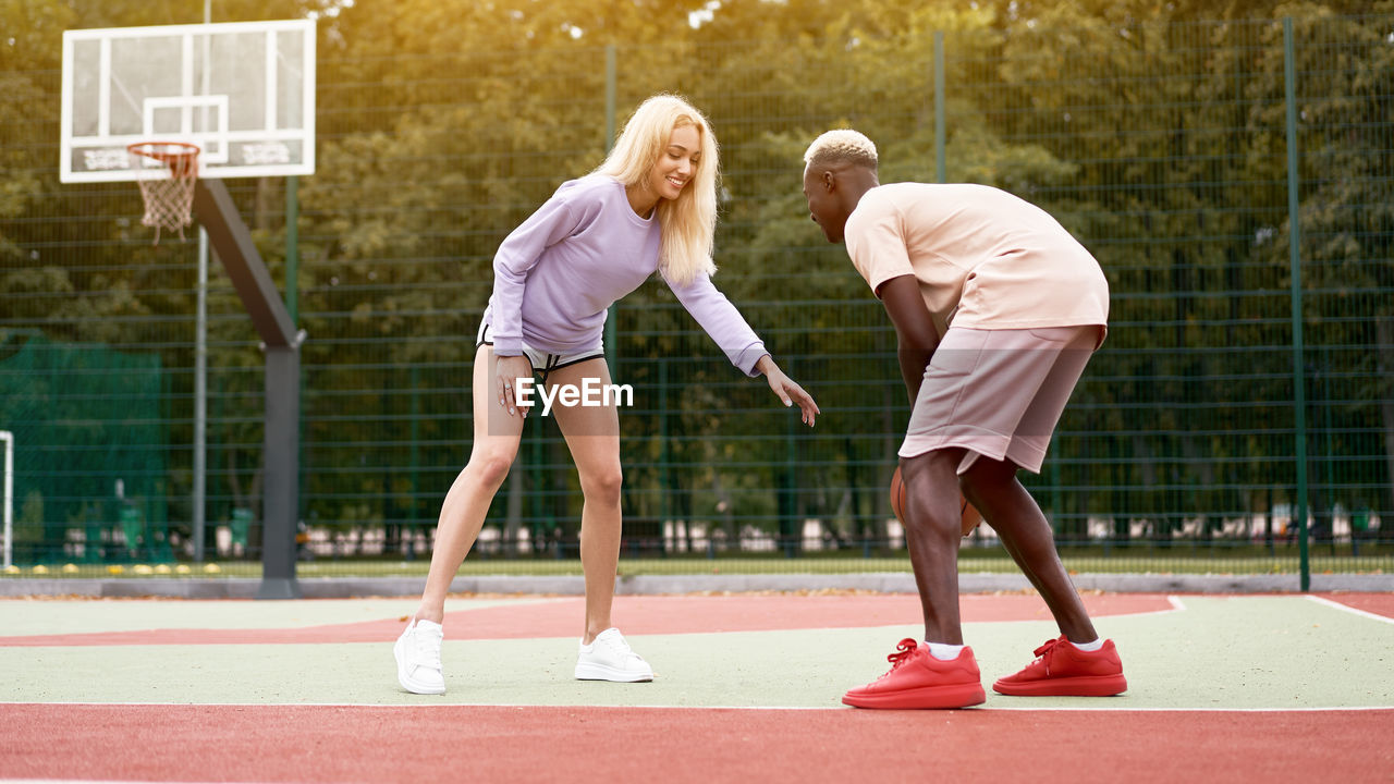 Young man and woman playing basketball