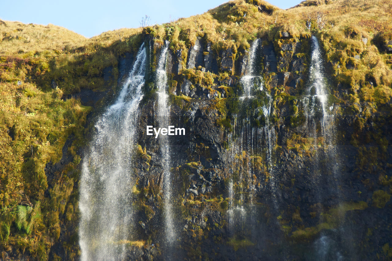 SCENIC VIEW OF WATERFALL AGAINST MOUNTAIN