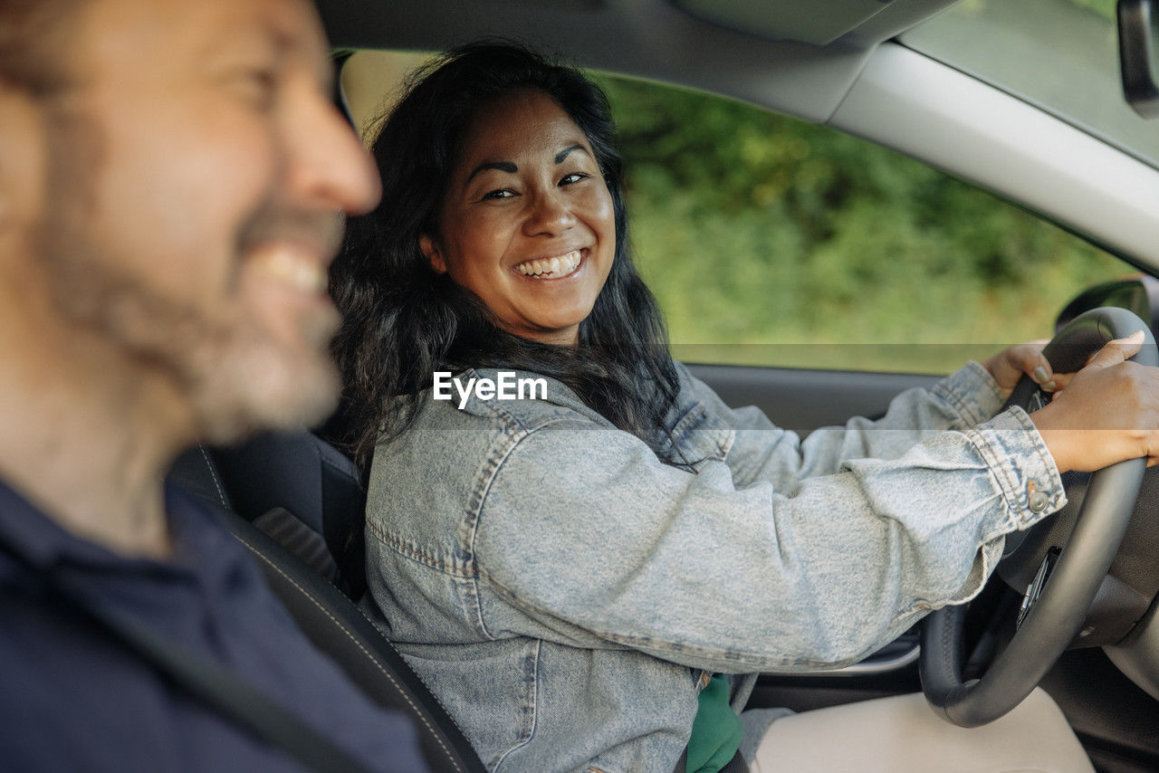 Smiling woman looking at man while driving car