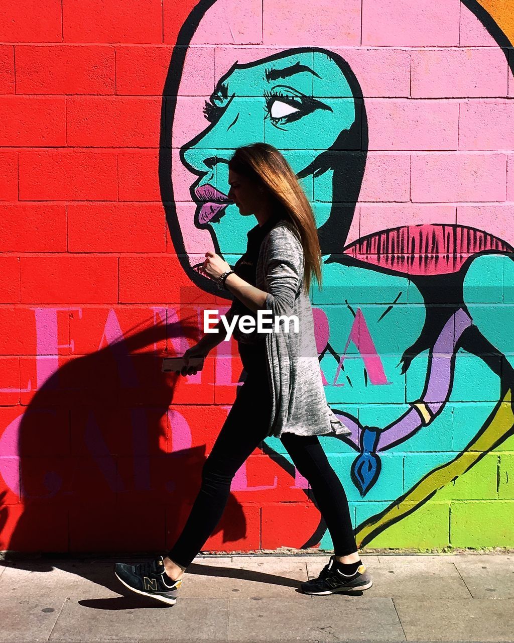 SIDE VIEW OF WOMAN STANDING AGAINST WALL