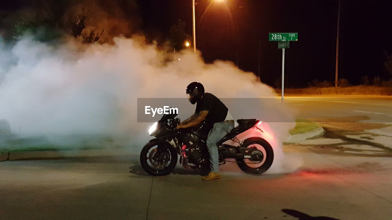 Side view of man practicing burnout at night