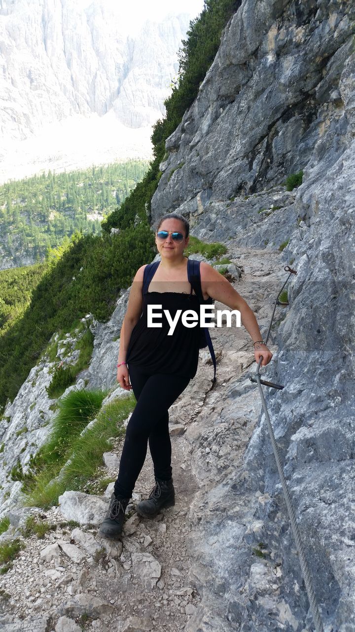 Full length of female hiker standing on rocky mountain