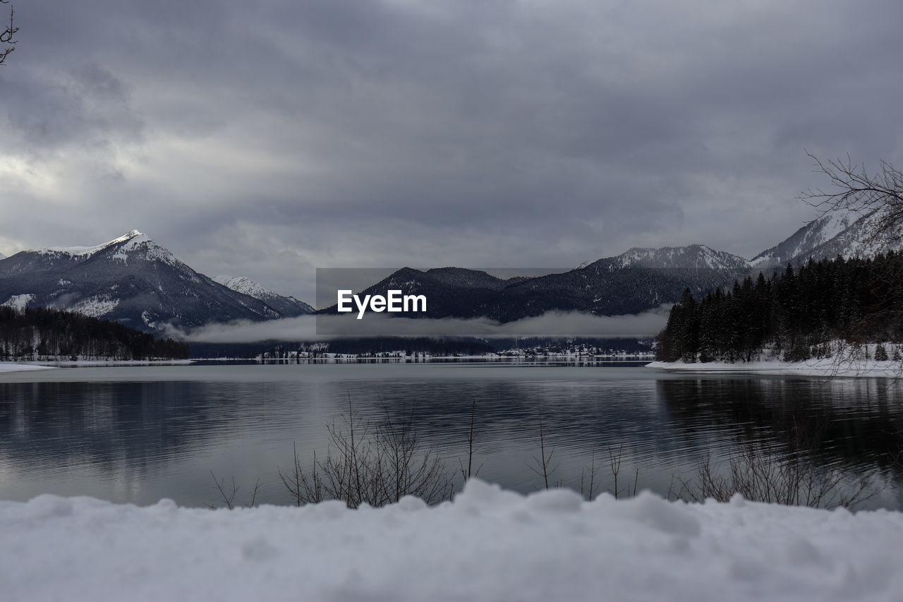 Scenic view of lake by snowcapped mountains against sky