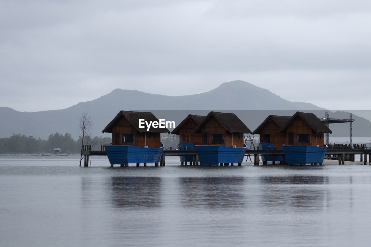 Houses by lake against sky