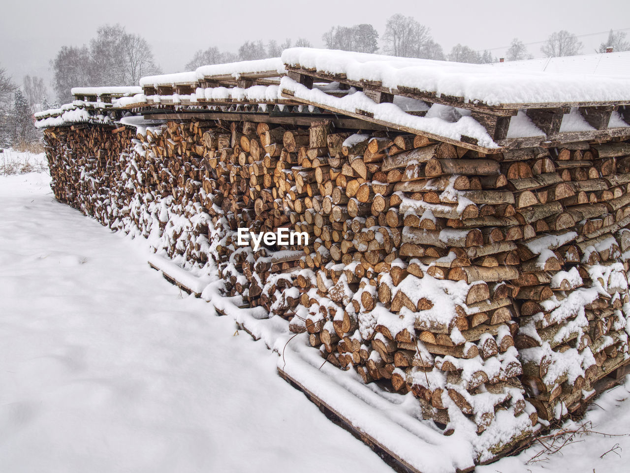 Chopped stock of firewood under snow, regular pile from cut wood