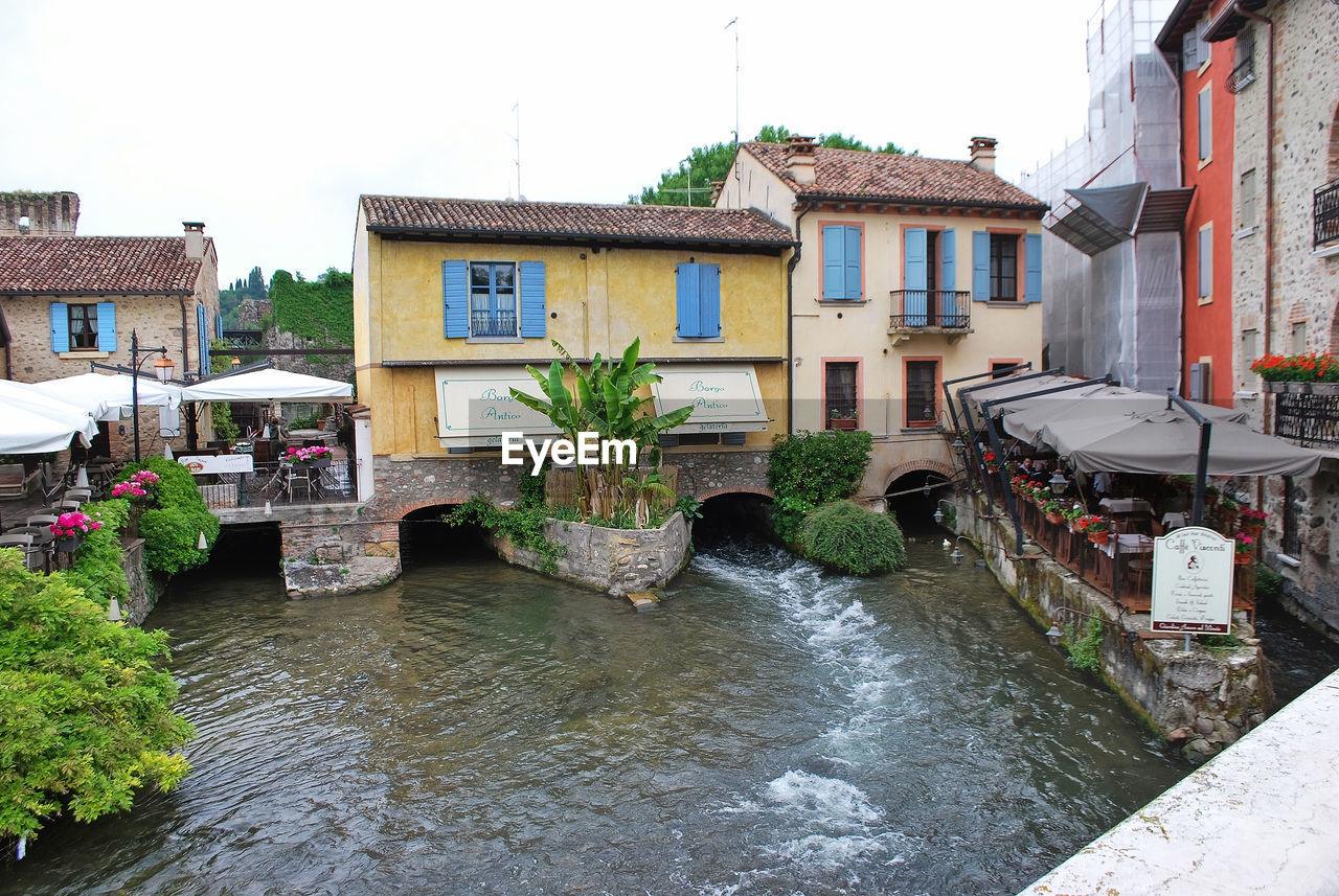 BUILDINGS BY RIVER AGAINST SKY