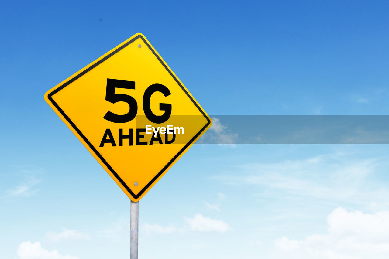 Low angle view of road sign against blue sky