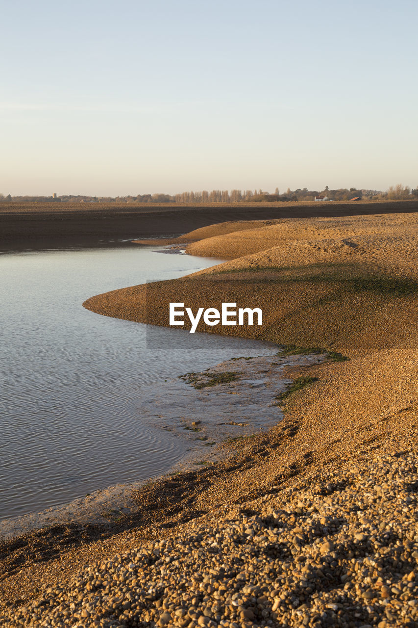 Scenic view of beach against clear sky during sunset