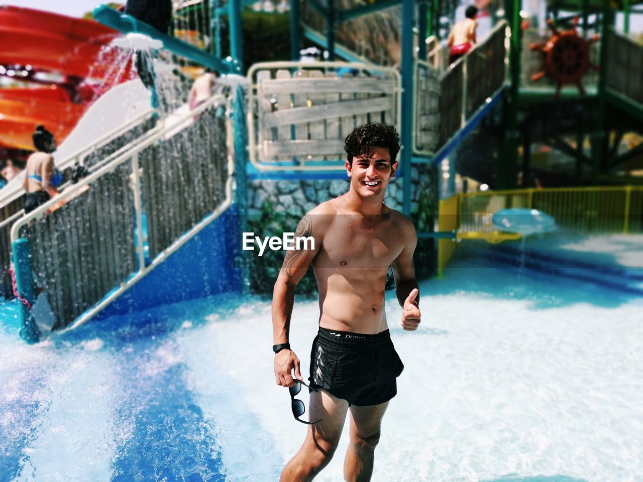 FULL LENGTH OF SHIRTLESS YOUNG MAN SWIMMING IN POOL