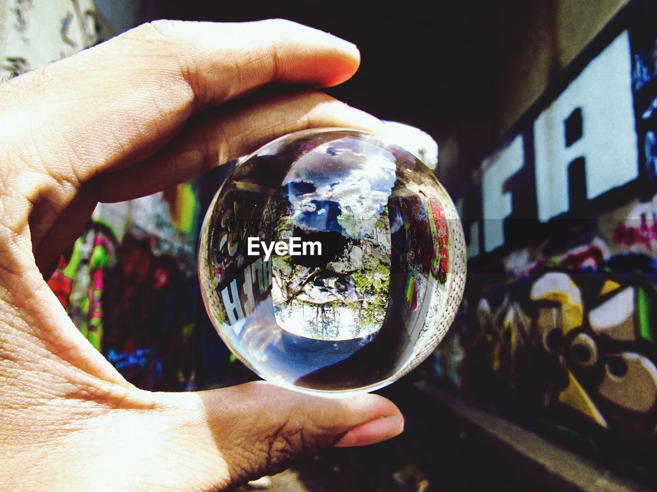 CLOSE-UP OF HAND HOLDING CRYSTAL BALL WITH REFLECTION
