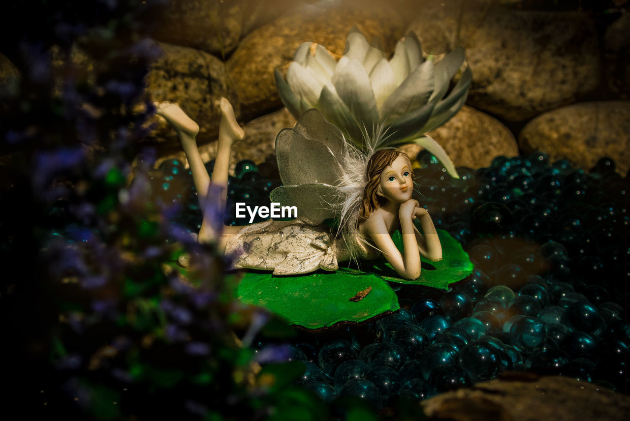 HIGH ANGLE VIEW OF WOMAN SITTING ON ROCK IN WATER