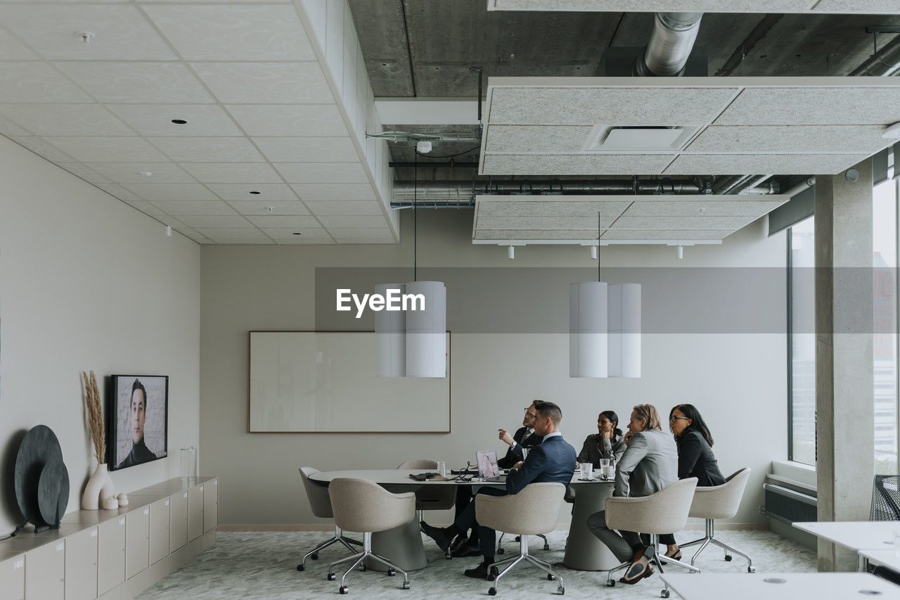 Multiracial business colleagues discussing strategy through video conference in board room