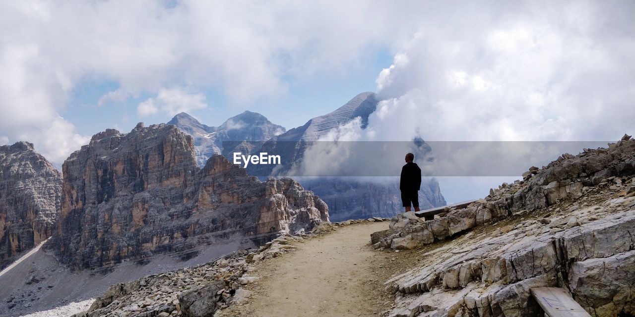 Rear view of man standing on mountain against sky