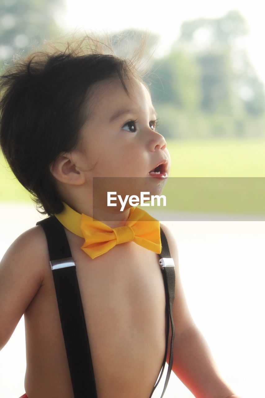 Close-up of shirtless baby boy wearing suspenders and bow tie