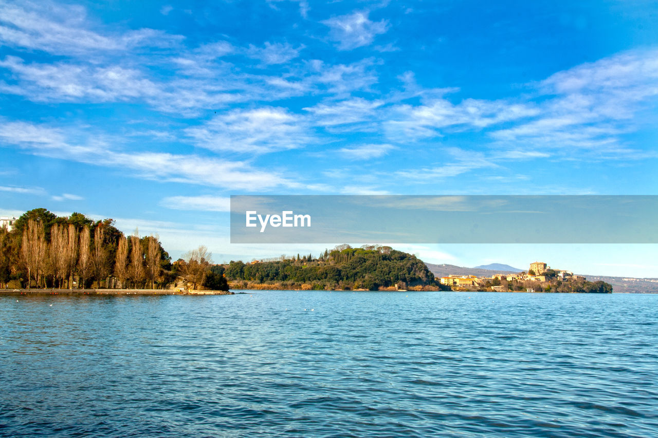 SCENIC VIEW OF SEA BY TREES AGAINST BLUE SKY